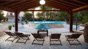 Une terrasse extérieure avec des chaises en bois et une fontaine en pierre.