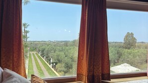 Une chambre avec un lit, une vue sur un paysage verdoyant et une fenêtre avec des rideaux.