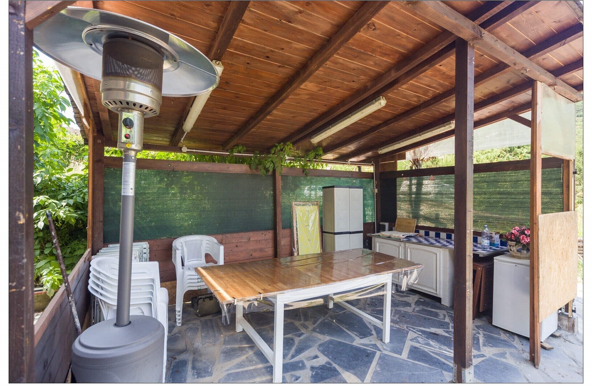 Eine Terrasses mit Tisch, Stühlen, Deckenventilator und Kühlschrank.