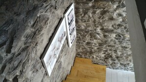 A stone wall with framed pictures and a wooden floor. - Casa Rosa "Casa Stefano" (Pian dei Manzi)