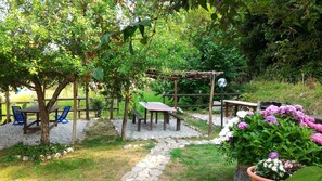 Un jardin agrémenté d’une pergola en bois, d’une table et de chaises, ainsi que d’un chemin pavé de pierres.