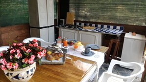 A kitchen with a stove, refrigerator, and a dining table set with plates, glasses, and a flower vase. - Casa Rosa "Casa Stefano" (Pian dei Manzi)