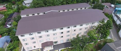 A multi-story building with a flat roof, surrounded by greenery and other residential buildings.