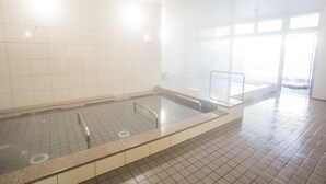 A large indoor swimming pool with clear water, tiled walls, and a tiled floor.
