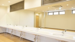 A long, white bathroom with multiple sinks and mirrors.