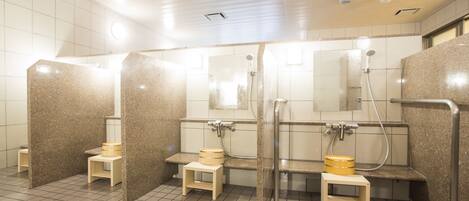 A public restroom with multiple stalls, each equipped with a toilet, a sink, and a mirror.