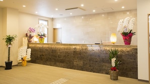 A reception area with a stone counter, potted plants, and a reception desk.