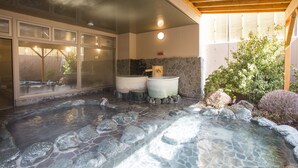 A spa area with a hot tub, stone flooring, and a view of the outdoors.