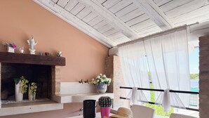 A cozy outdoor seating area with a table, chairs, a fireplace, and a view of greenery. - VIOLET Luxury Apt in Villa, Patio, Pool, Hot Jacuzzi, A/C, WiFi, Gym, Sauna (San Pietro di Cavarzere VE)