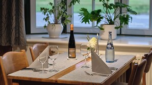 Una mesa de comedor dispuesta con copas de vino, una botella de vino y una botella de agua.
