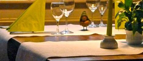 A table set with wine glasses, a small bird figurine, and a candle.