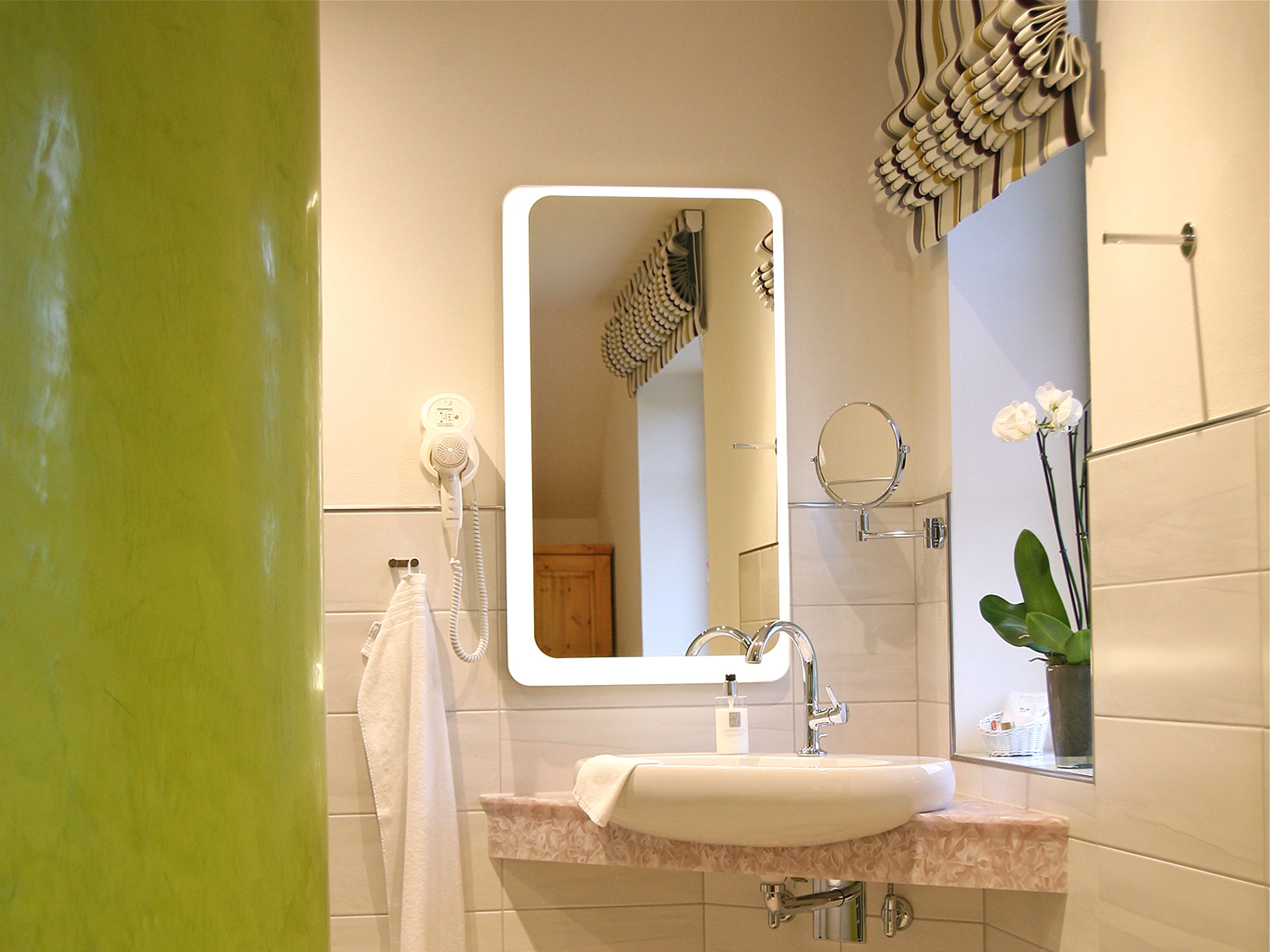 A bathroom with a sink, mirror, towel rack, and a shower area.