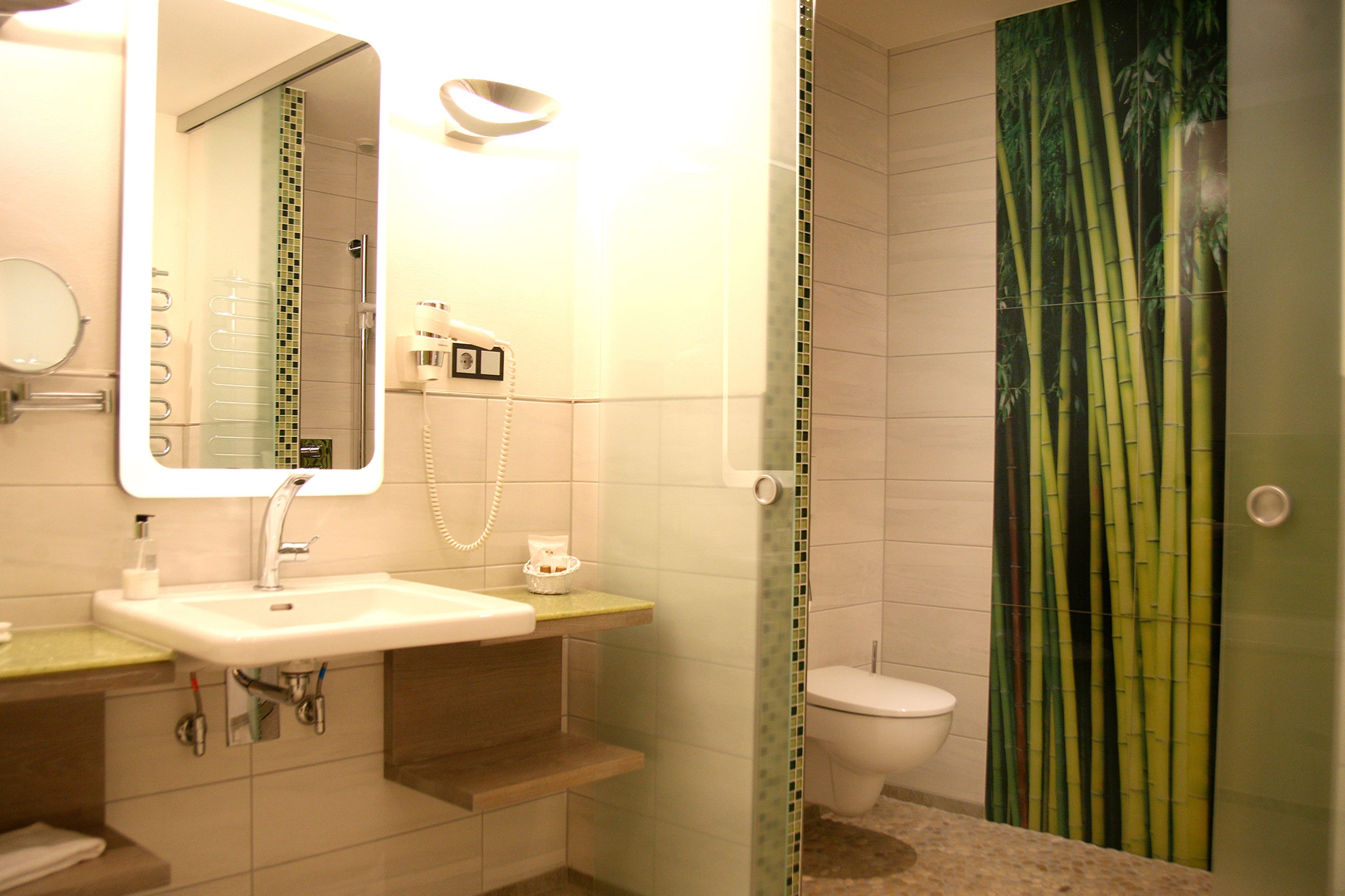 A bathroom with a sink, mirror, toilet, and shower curtain.
