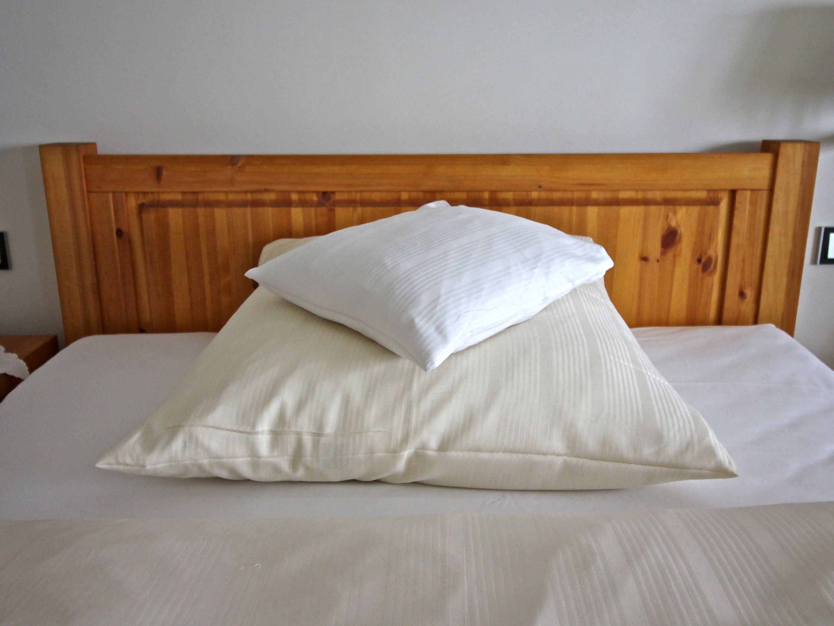 Una cama con cabecera de madera y dos almohadas.
