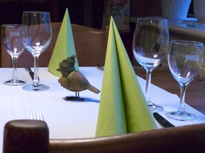 Una mesa de comedor con cuatro copas de vino y una figurita de pájaro.