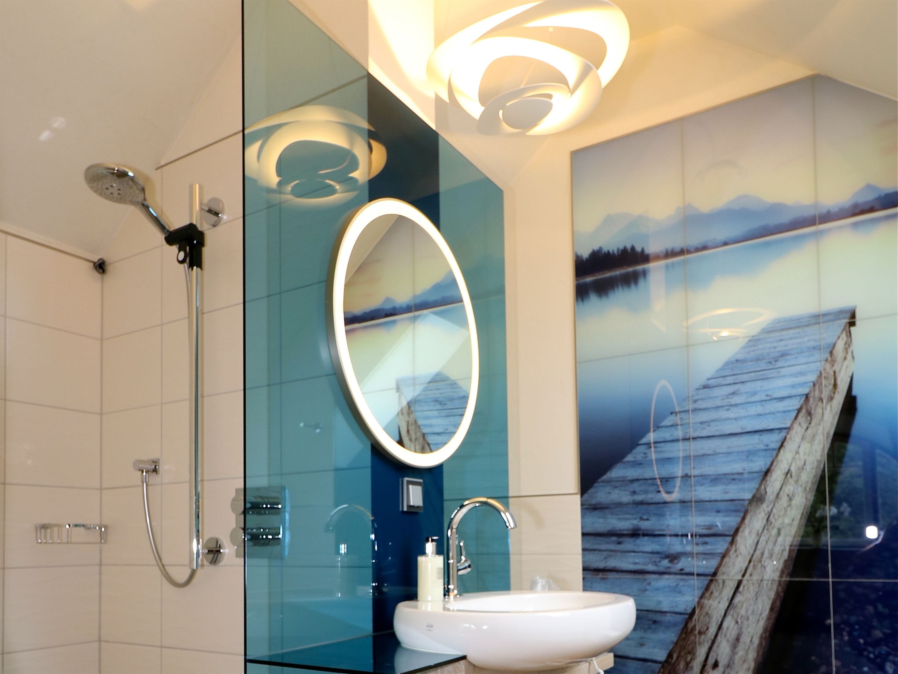 Un baño moderno con cabina de ducha de vidrio, un lavabo blanco y un espejo grande.