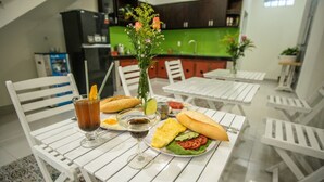 A dining table with a meal, a drink, and a vase of flowers. - D Central Homestay Hoi An (Da Nang)