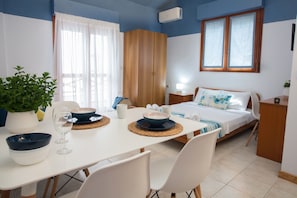 Cozy retreat with a neatly arranged bed, bedside table, and dining area for two.