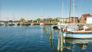 Un port de plaisance où sont amarrés de nombreux bateaux, avec des pilotis en bois et des bâtiments en arrière-plan.