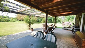 Une terrasse extérieure avec une table et des chaises, un barbecue et un espace abrité agrémenté d’une pergola.