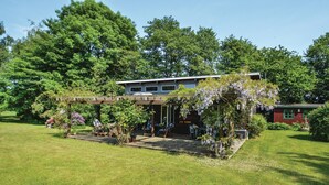 Une maison à deux étages avec un patio couvert et un jardin.