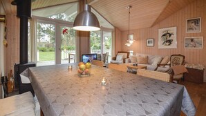 Ein gemütliches Zimmer mit einem großen Tisch, Korbmöbeln und einem Kamin.