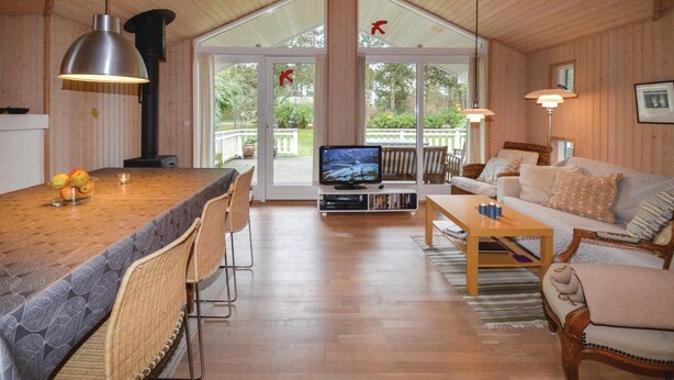 Ein gemütliches Wohnzimmer mit Holzboden, einem Fernseher, einer Couch und einem Essbereich mit Stühlen und einem Tisch.