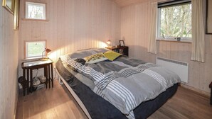 Ein gemütliches Schlafzimmer mit Bett, Nachttischen, einem Fenster und einer Heizung.
