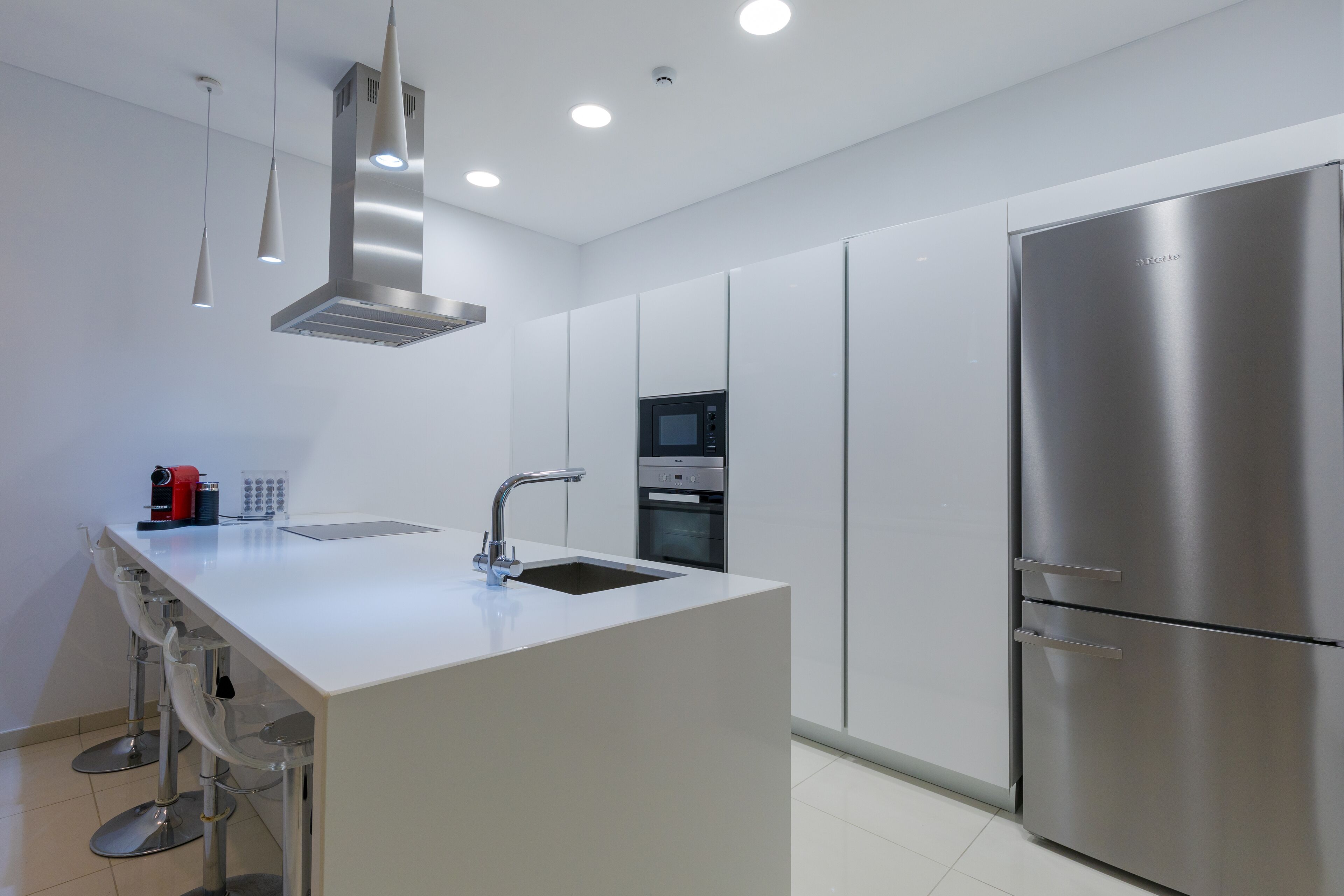 A modern kitchen with a central island, stainless steel appliances, and pendant lighting.