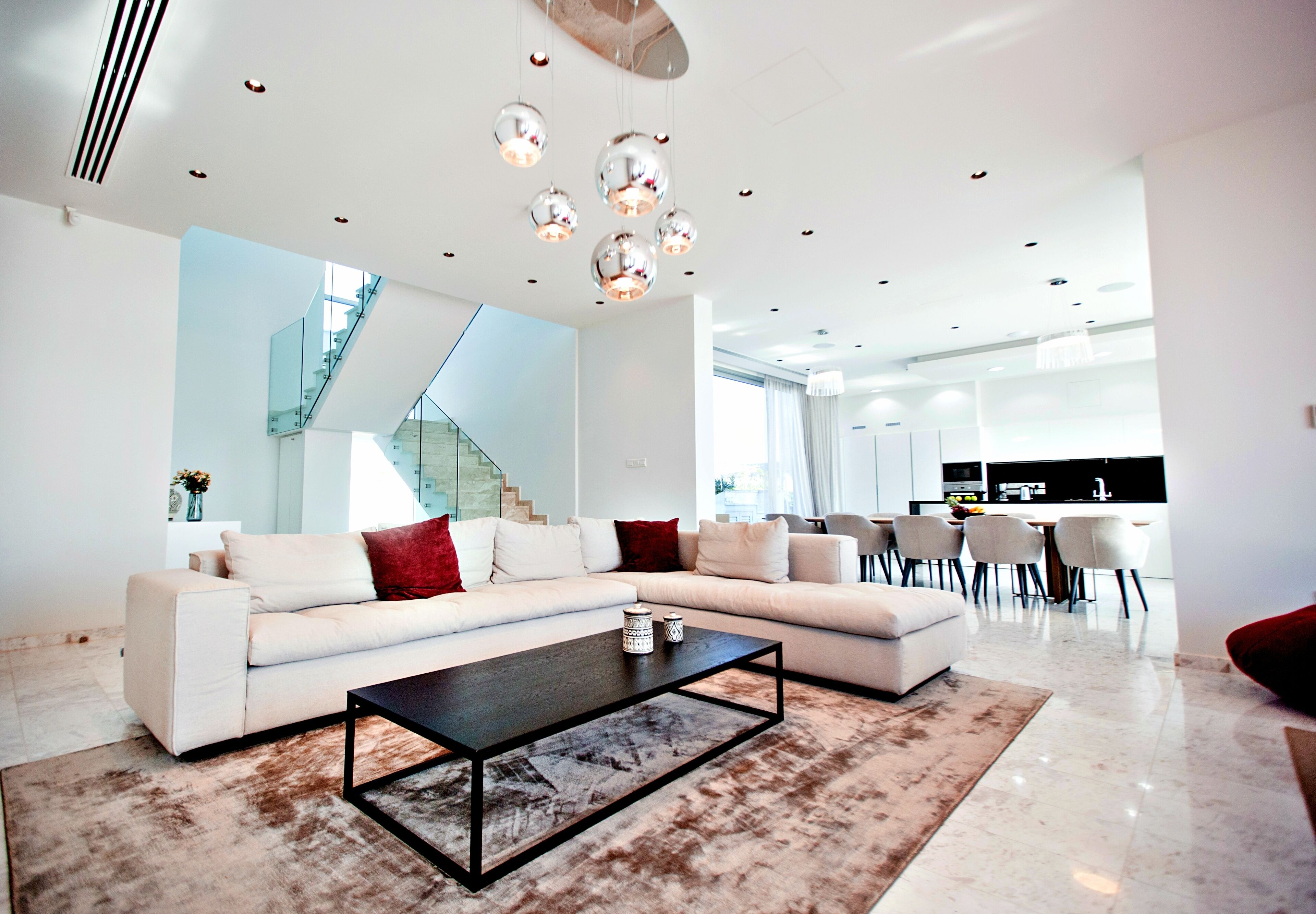 A modern living room with a sectional sofa, a coffee table, and a staircase leading to an upper level.