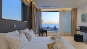 Habitación de hotel moderna con una cama grande, un escritorio, una silla y vistas al mar.