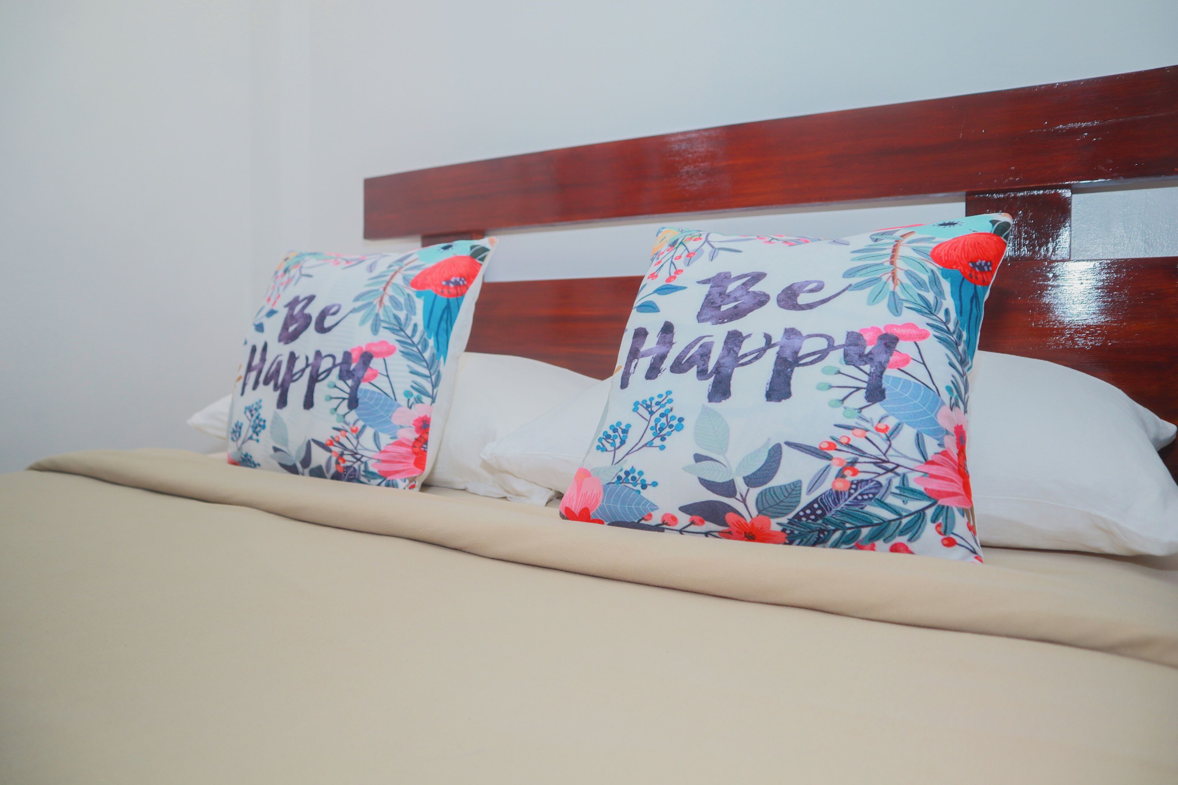 Un lit avec deux coussins décoratifs et une tête de lit en bois.