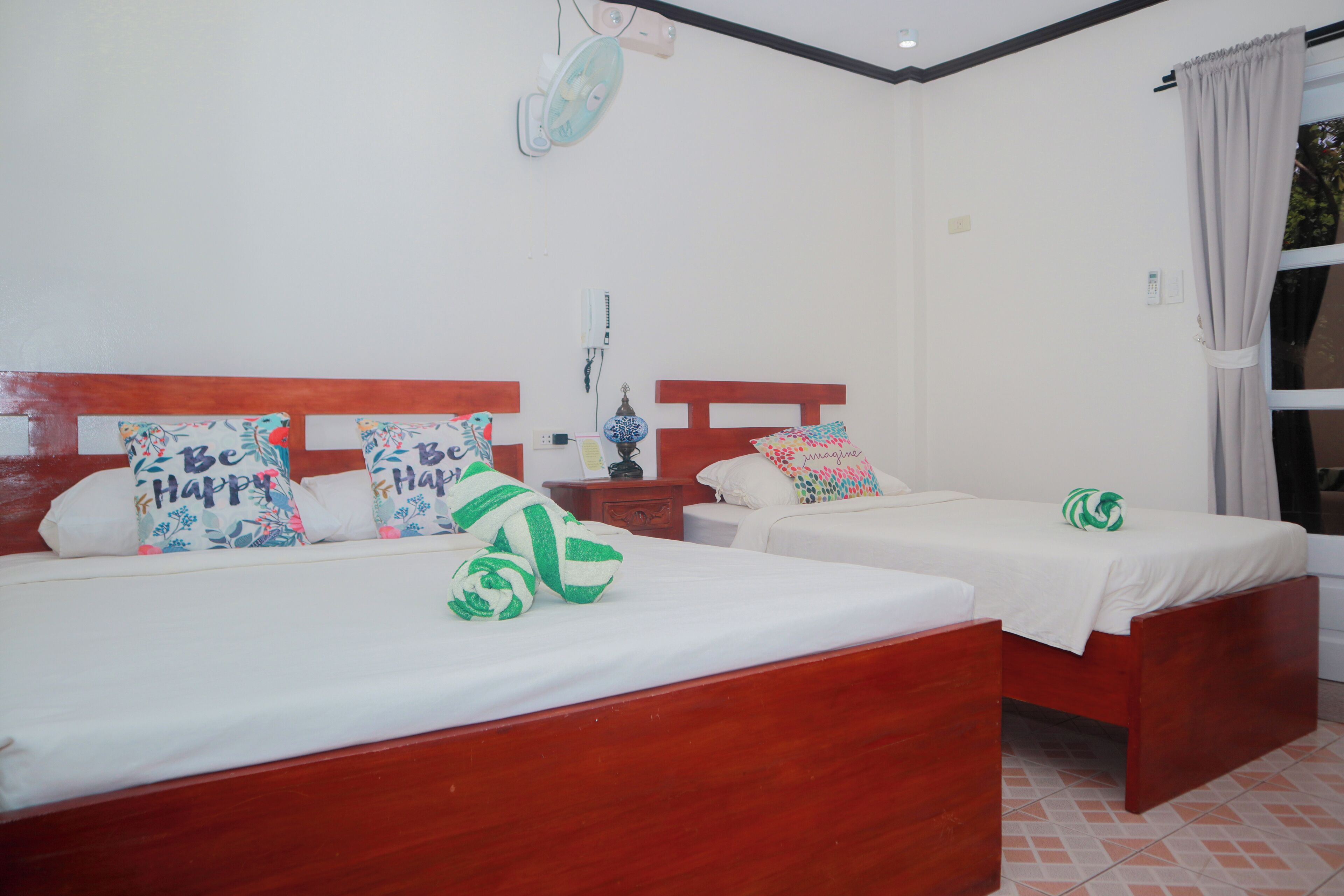 A hotel room with two wooden beds, white bedding, and colorful pillows.