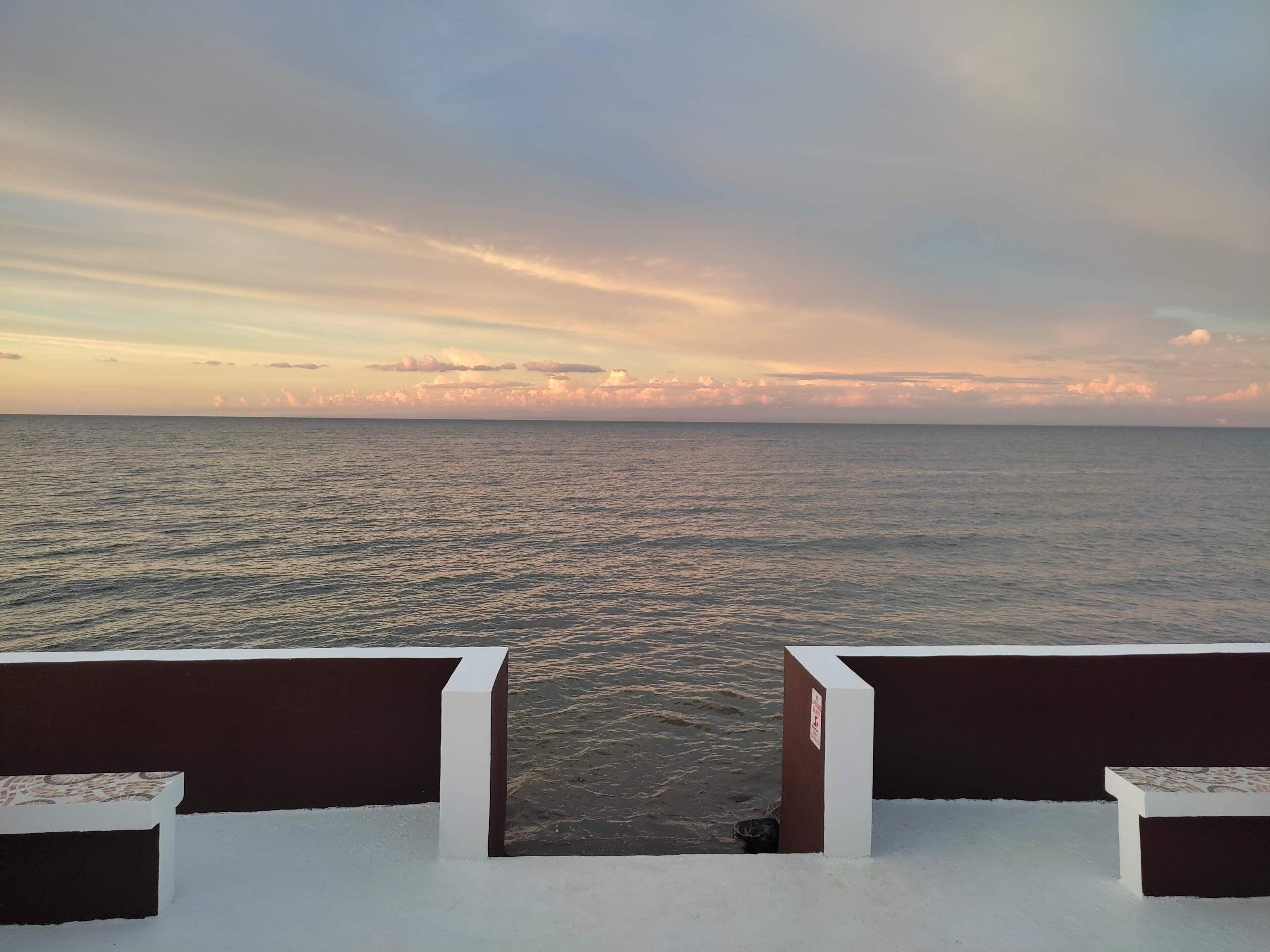 Vista de varanda com vista para o mar e céu claro.