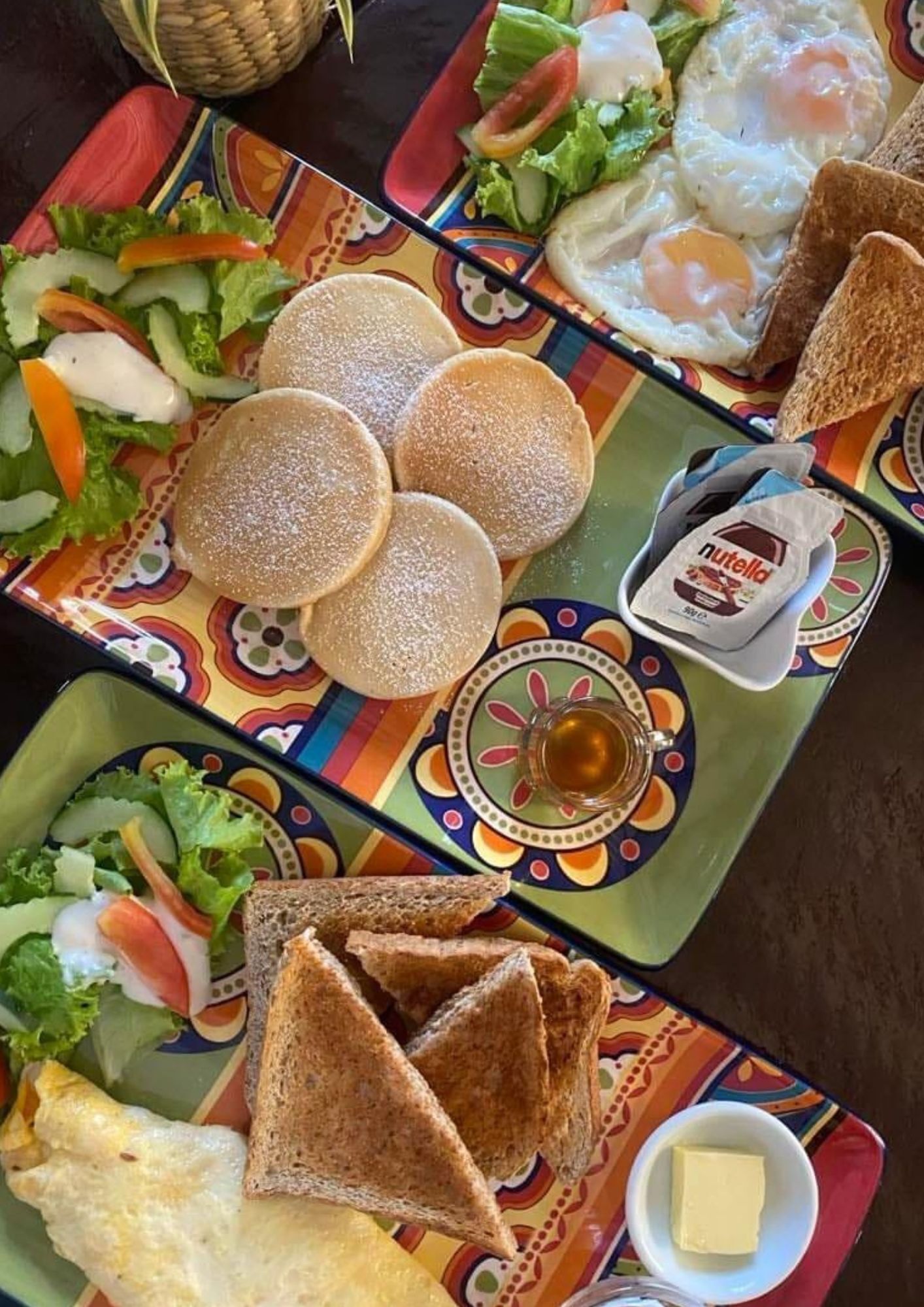 Ett färgglatt bord med olika frukosträtter, inklusive ägg, rostat bröd och en sallad.