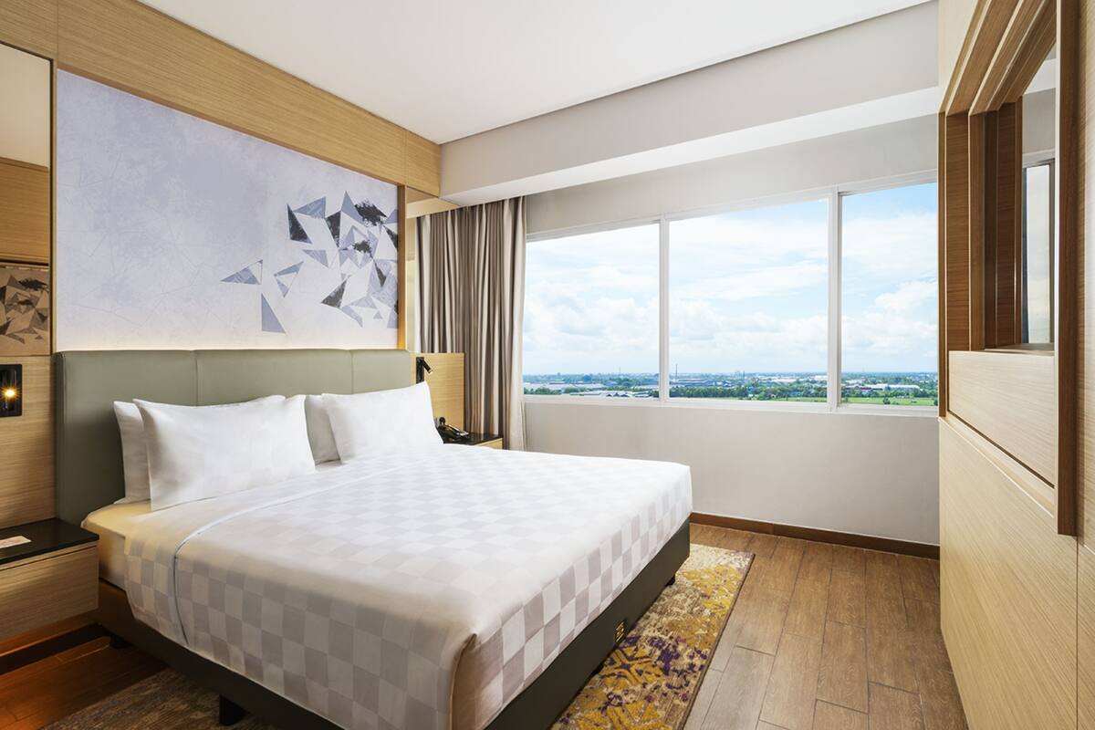 Una habitación de hotel con una cama grande, vistas a la ciudad y un diseño moderno.