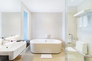 Un baño moderno con una bañera independiente, cabina de ducha con paredes de vidrio y un inodoro separado.