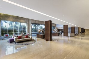 Un vestíbulo amplio con una zona de estar espaciosa, una recepción y vistas al exterior.
