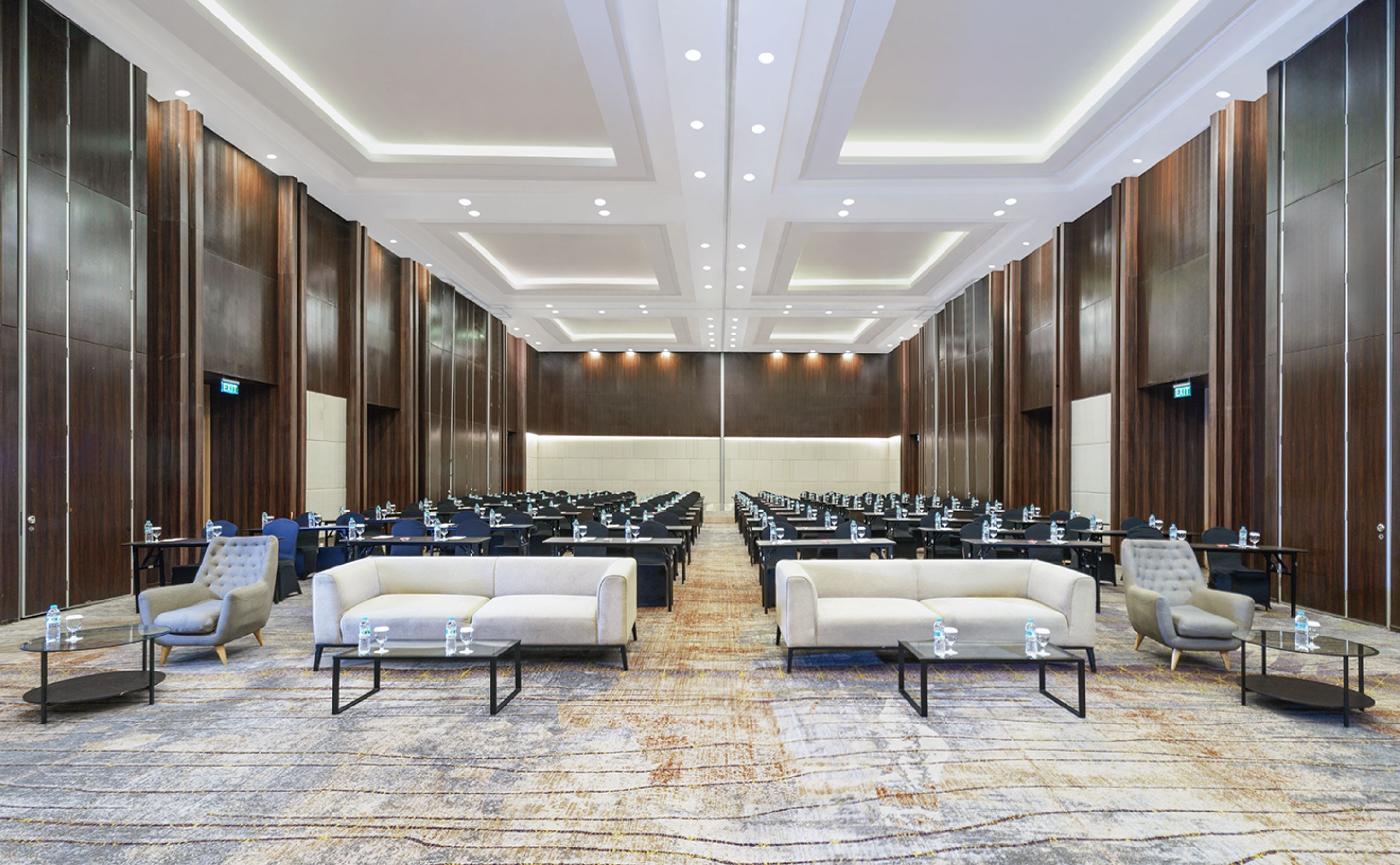 A large conference room with rows of tables and chairs, two sofas, and a carpeted floor.
