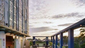 Una piscina con cubierta de madera, un área de juegos infantiles y vistas a un edificio alto con fachada geométrica.