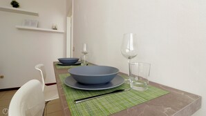 Ein Essbereich mit Tisch für zwei Personen, mit einer blauen Schüssel, einem Weinglas und einem klaren Glas.