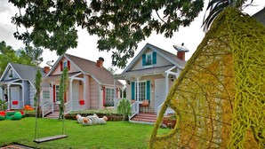 Una hilera de casas con césped bien cuidado, un columpio y una estructura amarilla decorativa.