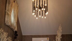 Un dormitorio con cama, ropa de cama blanca, un candelabro, aire acondicionado y decoración en las paredes.