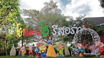 A garden with a white gazebo, a large sign with colorful letters, and various garden statues.