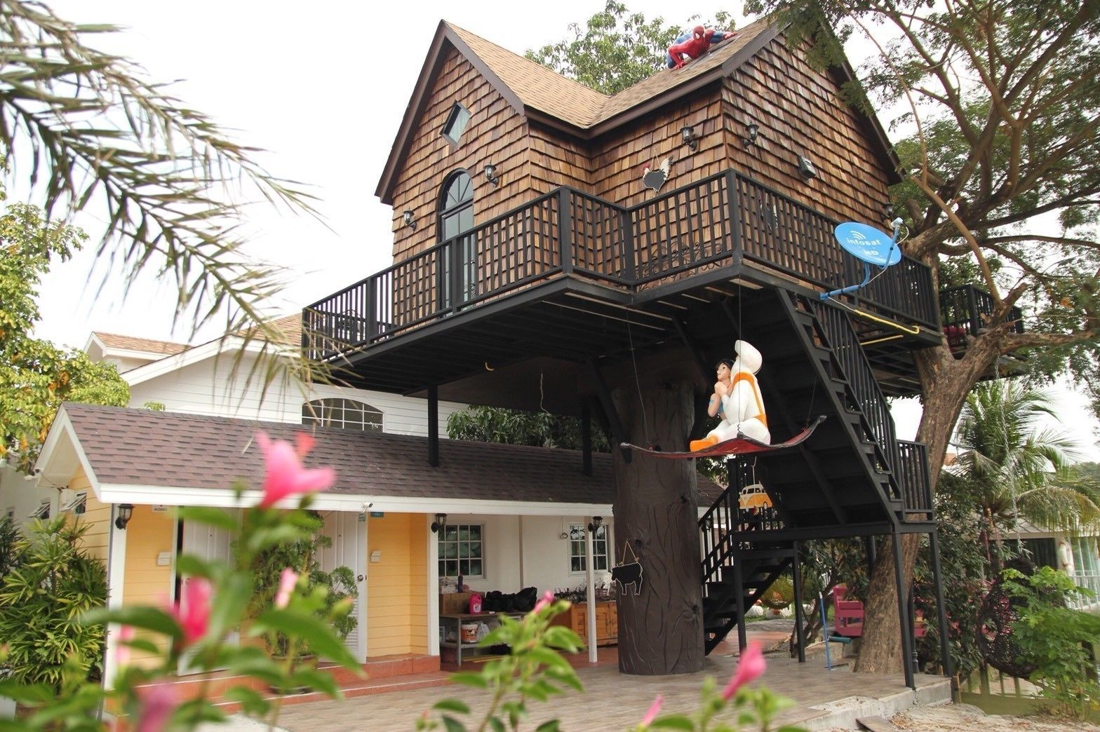 Une maison à laquelle est adossée une grande cabane dans les arbres.