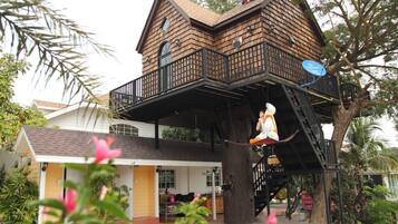 Une maison à laquelle est adossée une grande cabane dans les arbres.