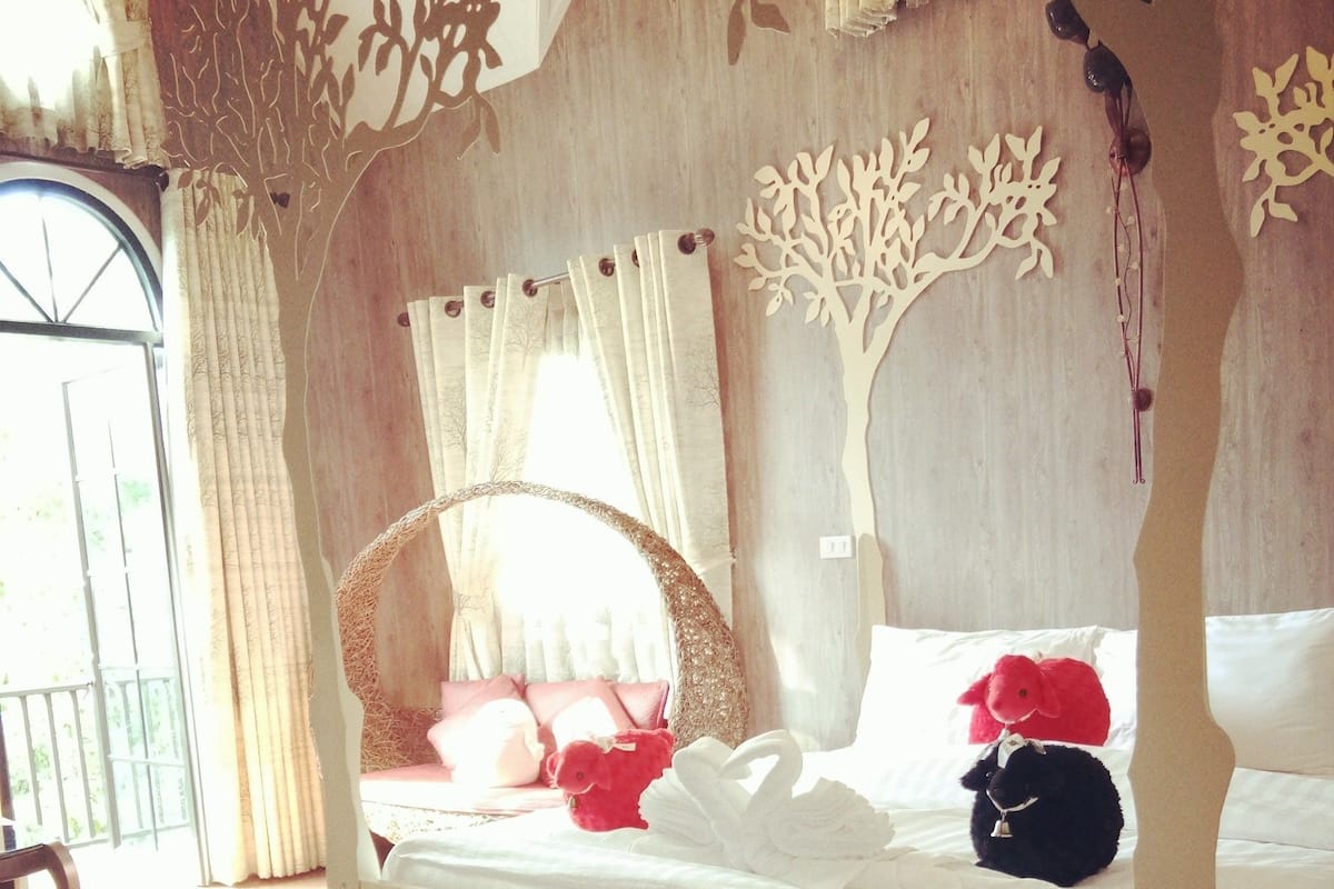 A wooden four-poster bed with a canopy, white bedding, and decorative elements on the headboard.