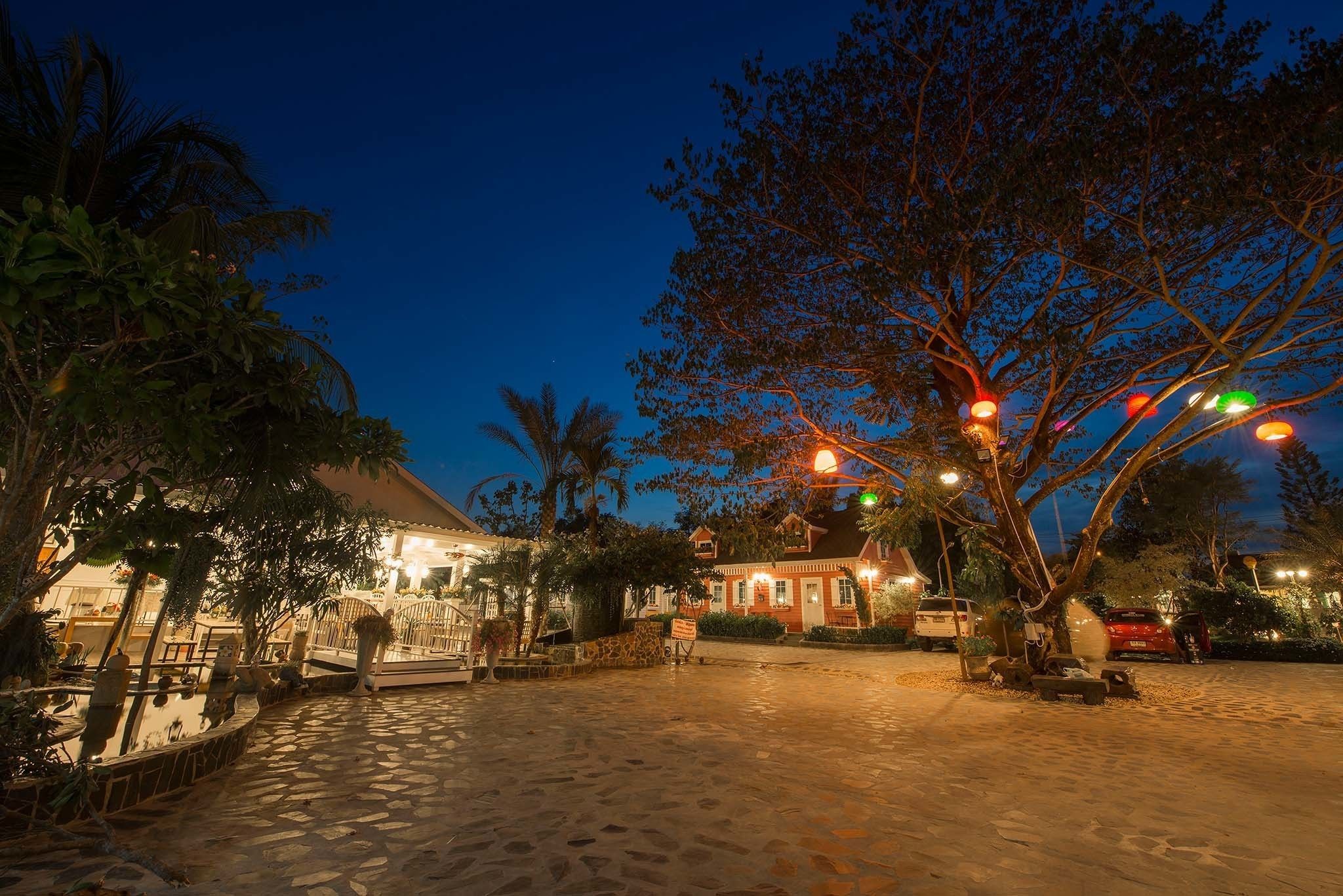 A nighttime view of a courtyard with a building, palm trees, and a paved walkway.