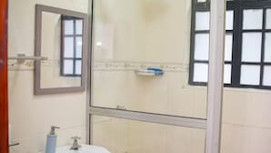 Une salle de bain avec un lavabo blanc, un miroir et une fenêtre à carreaux.
