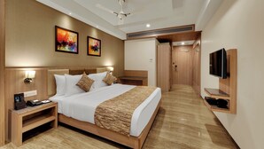 Une chambre d’hôtel avec un lit, des tables de chevet, une télévision et des œuvres d’art accrochées au mur.